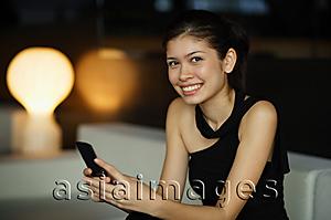 Asia Images Group - Young woman holding mobile phone, looking at camera