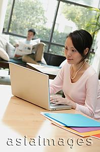 Asia Images Group - Couple at home, woman using laptop, man in background