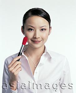 Asia Images Group - Young woman holding make-up brush to cheek