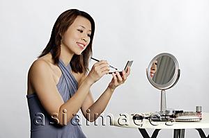 Asia Images Group - Woman sitting, applying make-up