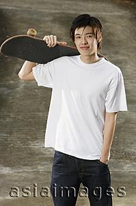 Asia Images Group - Young man holding skateboard over shoulder