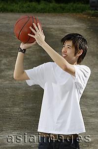 Asia Images Group - Young man holding basketball, aiming