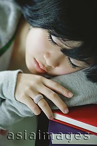 Asia Images Group - Young woman with head on stack of books, sleeping
