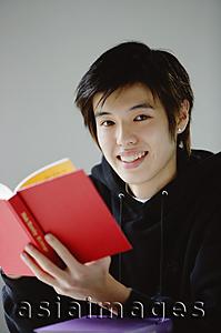 Asia Images Group - Young man with book smiling at camera