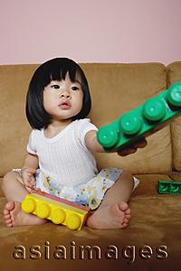 Asia Images Group - Young girl sitting on sofa, holding toys