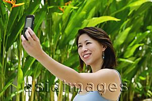 Asia Images Group - Woman outdoors, using mobile phone to take a picture of herself