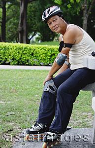 Asia Images Group - Mature adult with roller blades, sitting in park