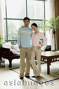 Asia Images Group - Couple standing in living room, looking at camera