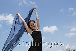 Asia Images Group - Woman in black dress, holding scarf in air