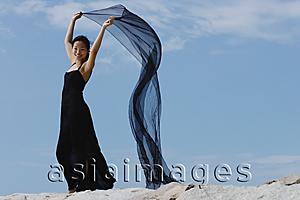 Asia Images Group - Woman in long black dress, holding scarf in air