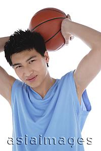 Asia Images Group - Young man holding basketball behind his head, smiling