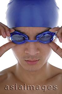 Asia Images Group - Young man adjusting swimming goggles