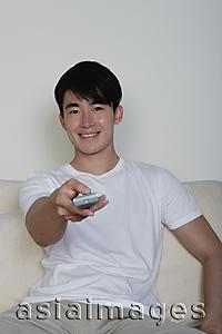 Asia Images Group - Young man, pointing TV remote control towards camera