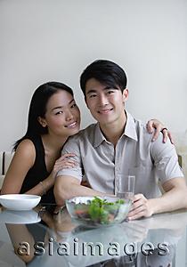 Asia Images Group - Couple sitting at dining table, looking at camera