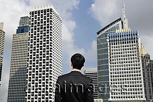 Asia Images Group - Businessman surrounded by buildings, rear view