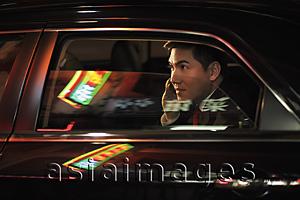 Asia Images Group - Man sitting in car talking on phone. Chinese characters reflected on the windows
