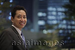 Asia Images Group - Mature man wearing a suit and smiling in front of a lit building