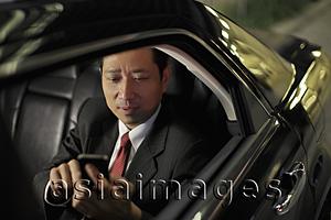 Asia Images Group - mature man sitting in a car texting on phone