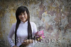 Asia Images Group - Young woman wearing traditional Vietnamese dress holding lotus flowers