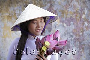 Asia Images Group - Young woman wearing traditional Vietnamese outfit holding lotus flowers