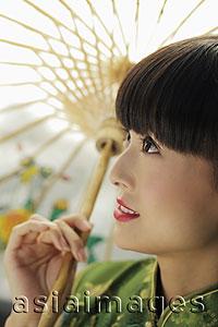 Asia Images Group - Profile of young woman looking up and holding an umbrella