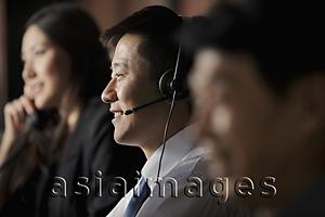 Asia Images Group - Closeup of man smiling with head set on, people in back ground