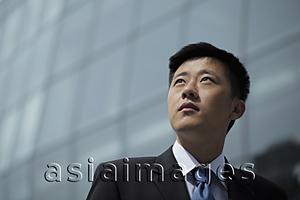 Asia Images Group - Young man in suit looking up, building in background