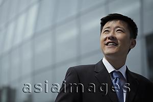 Asia Images Group - Young man wearing a suit, looking up smiling,