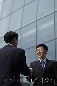 Asia Images Group - Businessmen shaking hands in front of a building