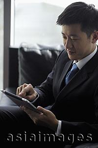 Asia Images Group - Young man wearing a suit, working on a tablet