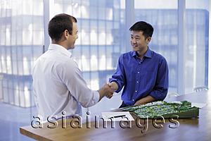 Asia Images Group - Young men shaking hands in modern offic