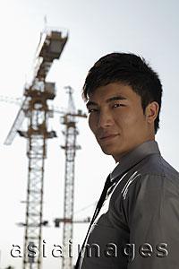 Asia Images Group - Young man standing in front of cranes