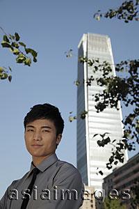 Asia Images Group - Portrait of young man standing in front of skyscraper, China