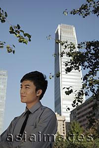 Asia Images Group - Profile of young man standing in front of skyscraper, China