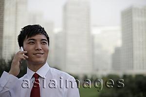 Asia Images Group - Young man talking on the phone in front of modern buildings