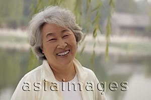 Asia Images Group - Head shot of older woman smiling beneath a tree