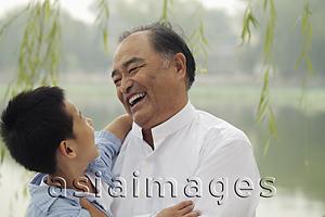 Asia Images Group - Head shot of grandfather and young boy smiling at each other