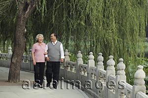 Asia Images Group - Older couple walking by a lake, smiling at each other