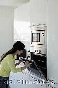 Asia Images Group - Young woman looking in oven