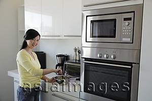 Asia Images Group - Young woman cooking in kitchen