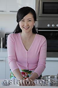 Asia Images Group - Woman cooking in kitchen and smiling