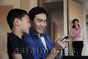 Asia Images Group - Father playing game with son on phone
