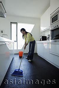 Asia Images Group - Woman sweeping her kitchen floor
