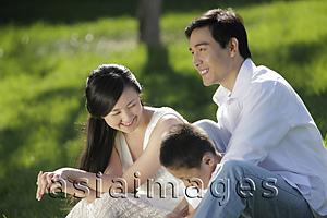 Asia Images Group - Young family sitting on the grass smiling