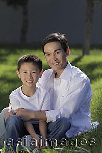 Asia Images Group - Father and son sitting on grass together smiling