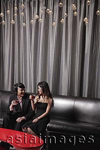 Asia Images Group - Young couple sitting in a club having a drink