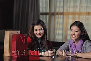Asia Images Group - Young women sitting at a cafe with shopping bags