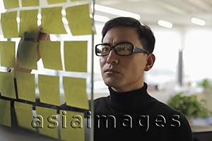 Asia Images Group - man wearing glasses looking at stick on notes