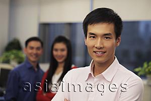 Asia Images Group - Head shot of man with two colleagues smiling behind him
