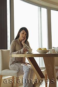 Asia Images Group - Young woman sitting at a table looking down